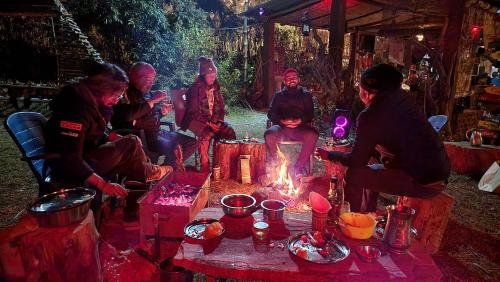 grupa ludzi siedzących przy ogniu w obiekcie Hobo Huts w mieście Panuānaula