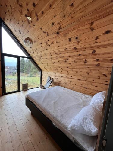 a bedroom with a wooden wall with a bed in it at Cabana Neagră in Beliş