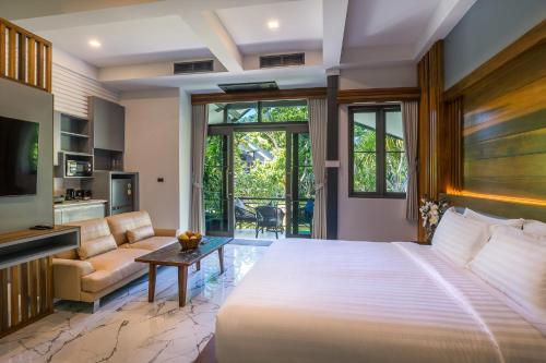 a bedroom with a large bed and a living room at Loy Chalet in Klong Muang Beach