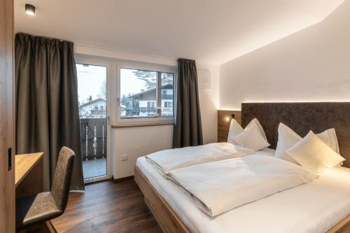 una camera d'albergo con letto e finestra di Alpenrose Alpine Living a Selva