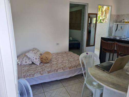 a small room with a bed and a table with a laptop at Pousada Beach Claudia in Maragogi