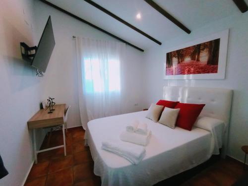 um quarto com uma cama branca e almofadas vermelhas em Casa de Campo Los Manueles Ideal Perros Pet Friendly em Gójar