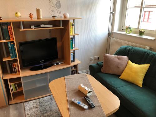 ein Wohnzimmer mit einem grünen Sofa und einem TV in der Unterkunft Pension Wunderbar in Naumburg