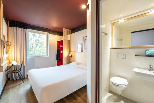 Un pequeño dormitorio con una cama blanca y un lavabo en Greet hotel Bourg-en-Bresse Sud Montagnat en Montagnat