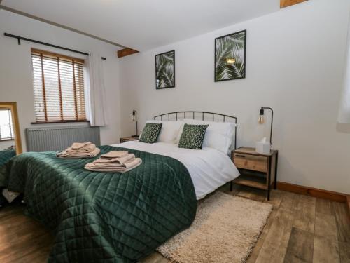 a bedroom with a bed with a green comforter at 1 Little Ripple Cottages in Canterbury