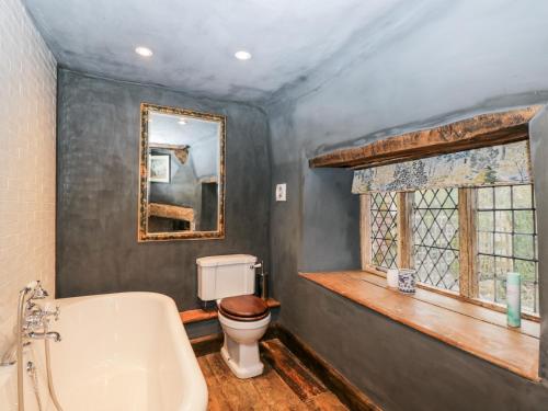 a bathroom with a tub and a toilet and a mirror at Foxden in Sherborne
