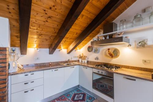 a kitchen with white cabinets and wooden ceilings at Baba Residences in Alassio