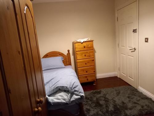 a bedroom with a bed and a wooden dresser at Hall 2 in Farnley