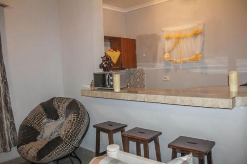 Zimmer mit einem Stuhl und einer Theke mit Stühlen in der Unterkunft Little Heaven's Home, 1 bedroom cozy home in Malindi