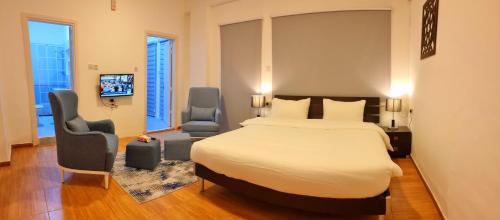 a hotel room with a large bed and two chairs at Byblos Aqaba in Aqaba