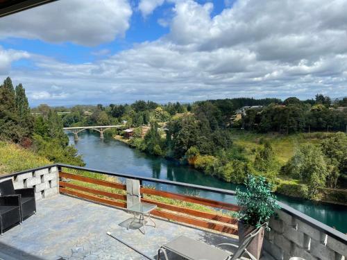 uma vista para um rio a partir de uma varanda com um banco em Altavista comodidad modernidad y seguridad em Ranco
