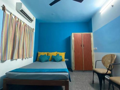 a blue bedroom with a bed and a chair at Unearth Hostel (Pondicherry) in Auroville