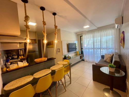 Una cocina y una sala de estar con mesa y sillas. en Flat Resort Beira Mar Porto de Galinhas, en Ipojuca