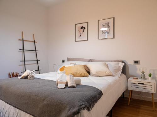 um quarto com uma cama com lençóis brancos e almofadas em Maison Blanche: appartamento elegante con parcheggio privato em Mantova