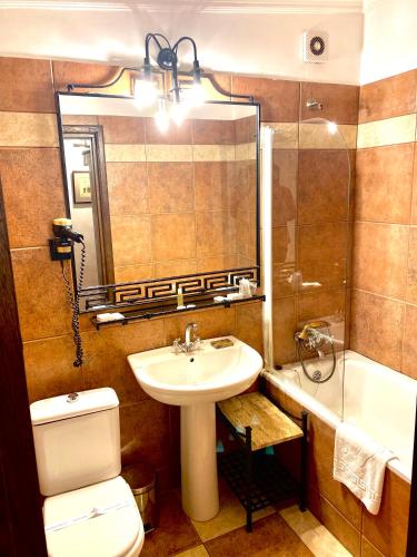 a bathroom with a sink and a toilet and a mirror at Apartamente Arcul de Triumf in Bucharest