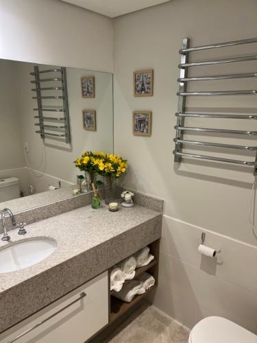 a bathroom with a sink and a vase of yellow flowers at Flat Completo Granja Brasil in Petrópolis