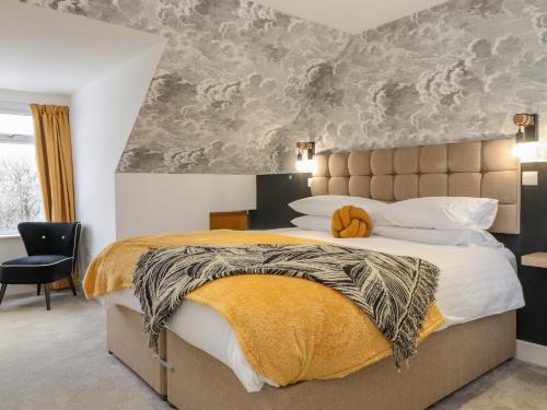 a bedroom with a large bed with a yellow blanket at Pheasants Folly in Windermere