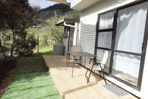 a table and chairs sitting on a deck next to a window at Cable Bay Farm in Nelson