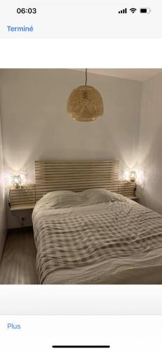 a bedroom with a large bed with a light on it at Chez L&L in Koksijde