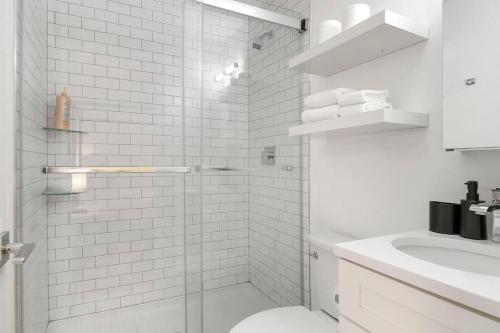 a white bathroom with a shower and a toilet at Modern 4BR Pilsen Apt near Restaurants - Racine 202 in Chicago