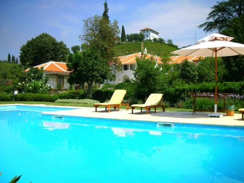 a swimming pool with two chairs and an umbrella at Casa da Azenha in Peso da Régua