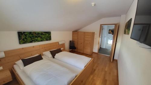 um quarto com uma grande cama branca e uma televisão de ecrã plano em Badl im Mühlbacher Talile em Gais