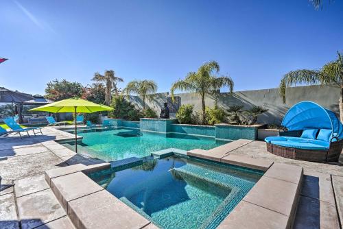 a swimming pool with blue chairs and an umbrella at Private Pool and Spa Spacious Home in Bermuda Dunes in Bermuda Dunes