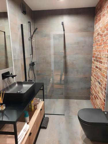 uma casa de banho com um lavatório preto e uma parede de tijolos em Patio Jazz em Koszalin