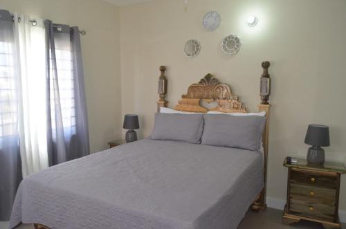 a bedroom with a bed and two lamps and clocks on the wall at Jamaica Tranquility in Lucea