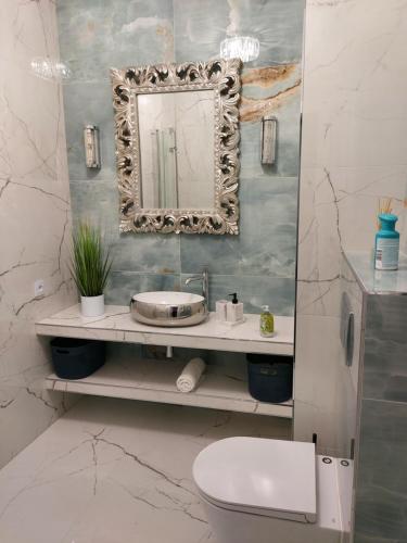 een badkamer met een wastafel, een spiegel en een toilet bij Patio Glamour in Koszalin