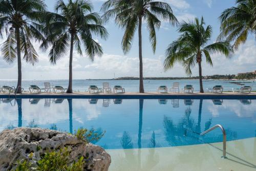 a swimming pool with palm trees and the ocean at CHAC at Chac Hal Al Puerto Aventuras in Puerto Aventuras