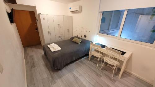 1 dormitorio con 1 cama y 1 mesa con sillas en Cozy studio - Palermo Chico en Buenos Aires