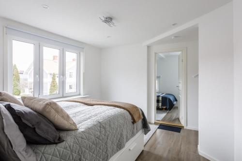 a white bedroom with a bed and a window at Flores 3 in Jönköping