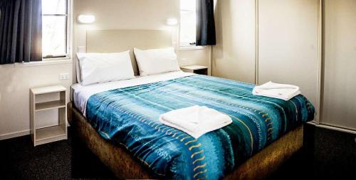 1 dormitorio con 1 cama grande y toallas. en Peace Resorts - Jervis Bay Holiday Cabins in Sussex Inlet, en Sussex Inlet