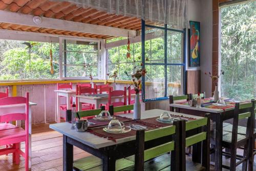 a dining room with tables and chairs and windows at Pousada das Brumas in Brumadinho