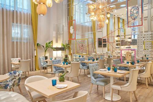 un restaurante con mesas, sillas y ventanas en NH Collection Madrid Abascal, en Madrid