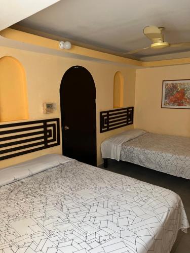 a bedroom with two beds and a black door at Hotel magallanes con cocineta 100 Metros de playa in Acapulco