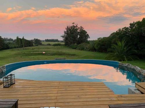 a pool with a wooden deck and a sunset at Casa de campo CLARA LUNA Sierra y Mar in Punta Ballena