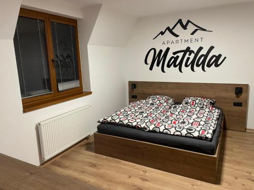 um quarto com uma cama e uma placa na parede em New Apartment Matilda - Tatranská Lomnica em Tatranská Lomnica