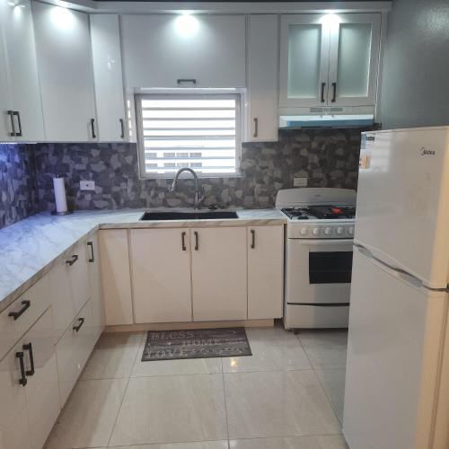 a kitchen with white cabinets and a sink and a refrigerator at Paradise Escape in Barceloneta