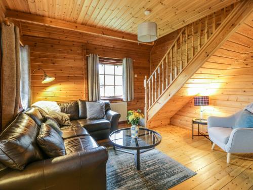 a living room with a leather couch and a table at Moyle Lodge in Dalbeattie