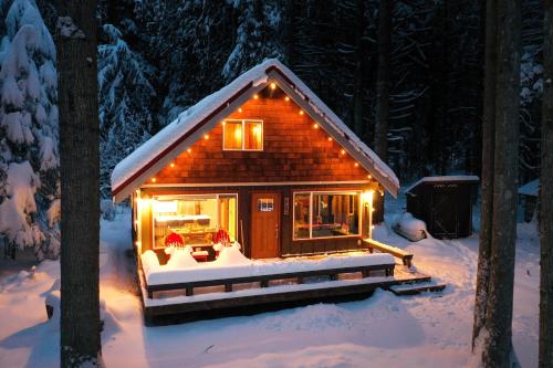 a small cabin in the snow with lights on at On Mountain Time in Glacier