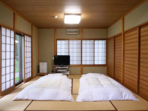 two beds in a room with windows and a tv at Forest Villa Yamanakako in Yamanakako