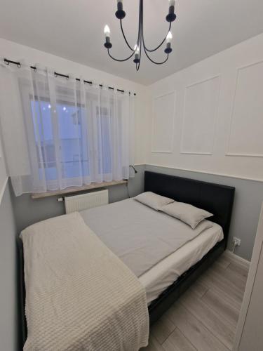 a bedroom with a large bed with a chandelier at 68 - Apartamenty Siedlce - Nowy apartament w centrum przy ul. 3 Maja 51a in Siedlce