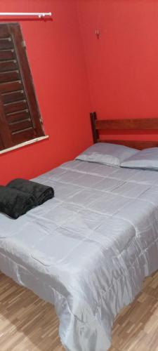 1 dormitorio con cama blanca y pared roja en Casa Friozinho da serra en Guaramiranga