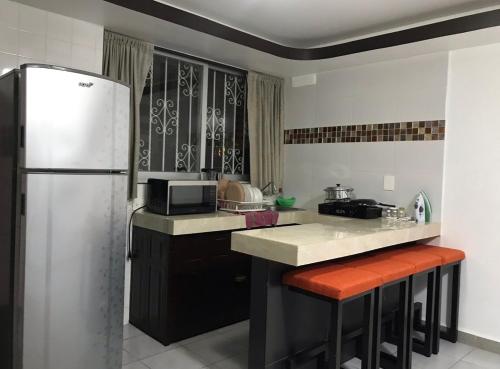 a kitchen with a refrigerator and a counter with stools at Hotel magallanes con cocineta 100 Metros de playa in Acapulco