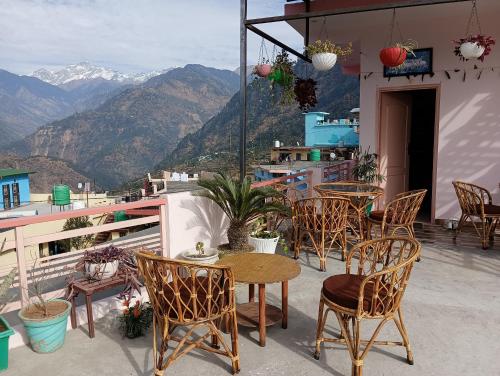 una mesa y sillas en un balcón con montañas en Kedar View Homestay en Ukhimath