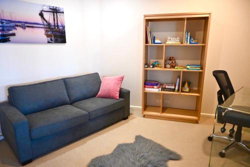 a living room with a blue couch and a desk at Sub Penthouse Luxe suit, CBD, secure parking, in Hobart