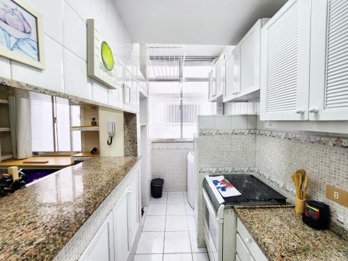 una cocina con armarios blancos y encimeras de mármol en Studio no Coração do Leblon JL311, en Río de Janeiro
