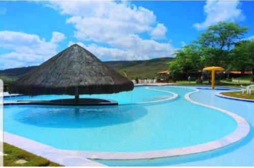 una gran piscina con techo de paja en Monte Castelo Gravatá Flat encantador, en Gravatá